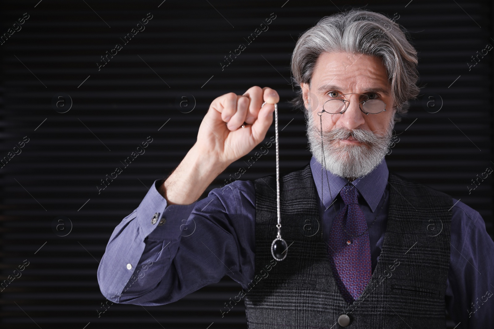 Photo of Psychotherapist with pendulum on black background. Hypnotherapy session