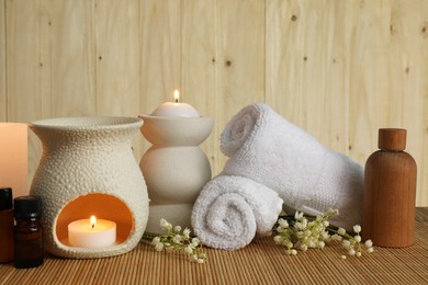Photo of Aromatherapy. Scented candles, bottles, flowers and towels on bamboo mat