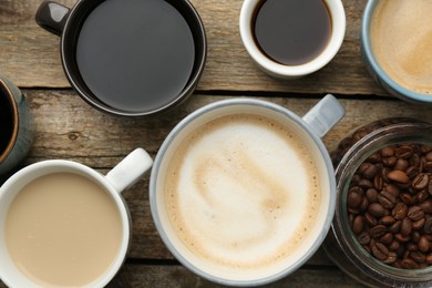 Photo of Different coffee drinks in cups and beans on wooden table, flat lay