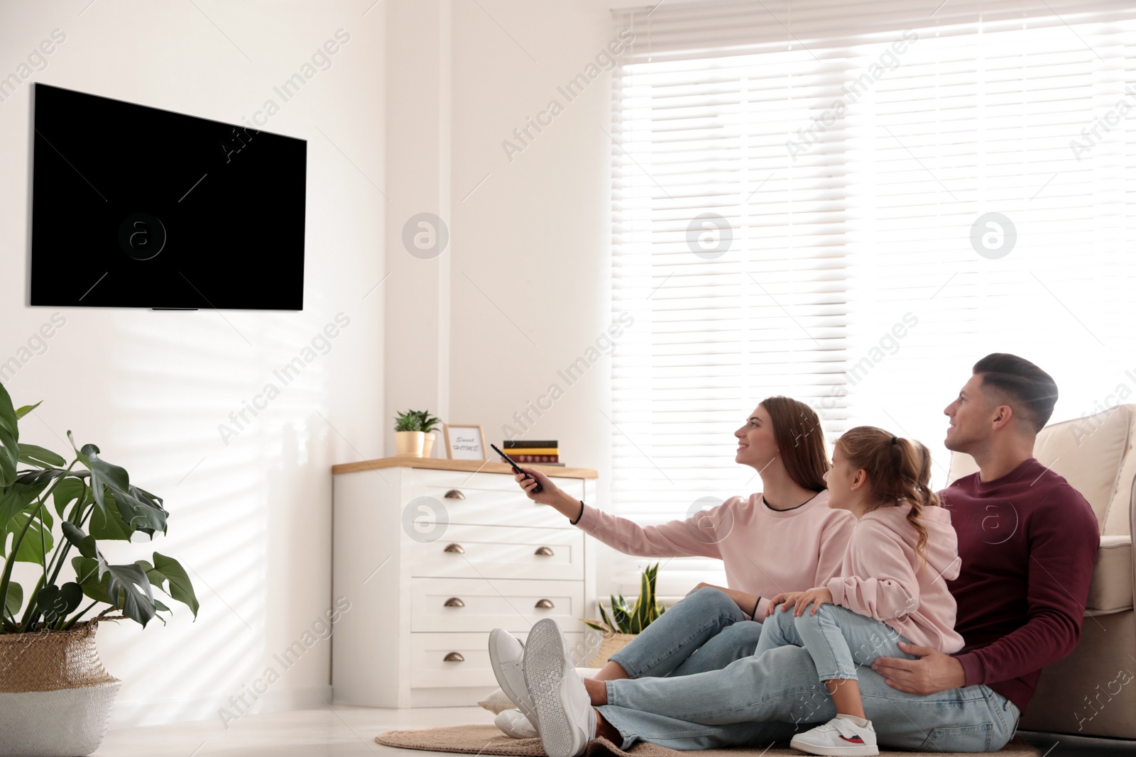 Photo of Happy family watching TV on floor at home