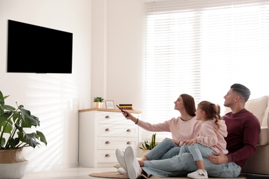 Photo of Happy family watching TV on floor at home