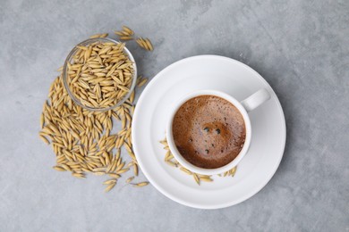Photo of Cup of barley coffee and grains on gray table, flat lay
