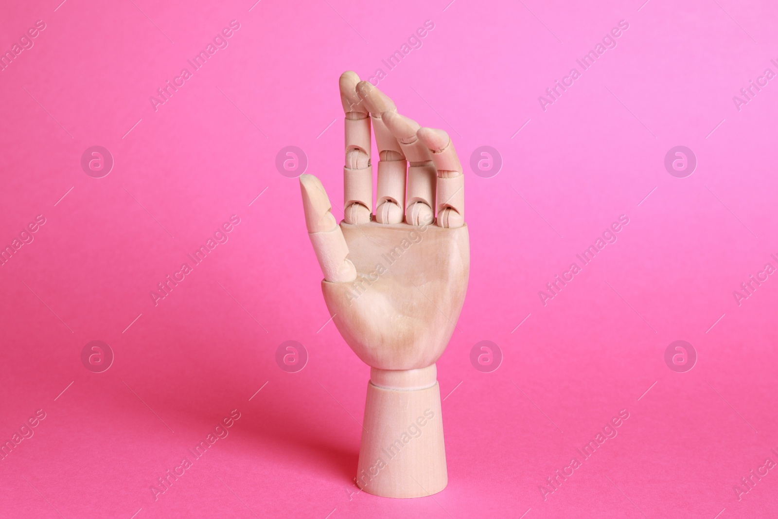 Photo of Wooden hand model on pink background. Mannequin part