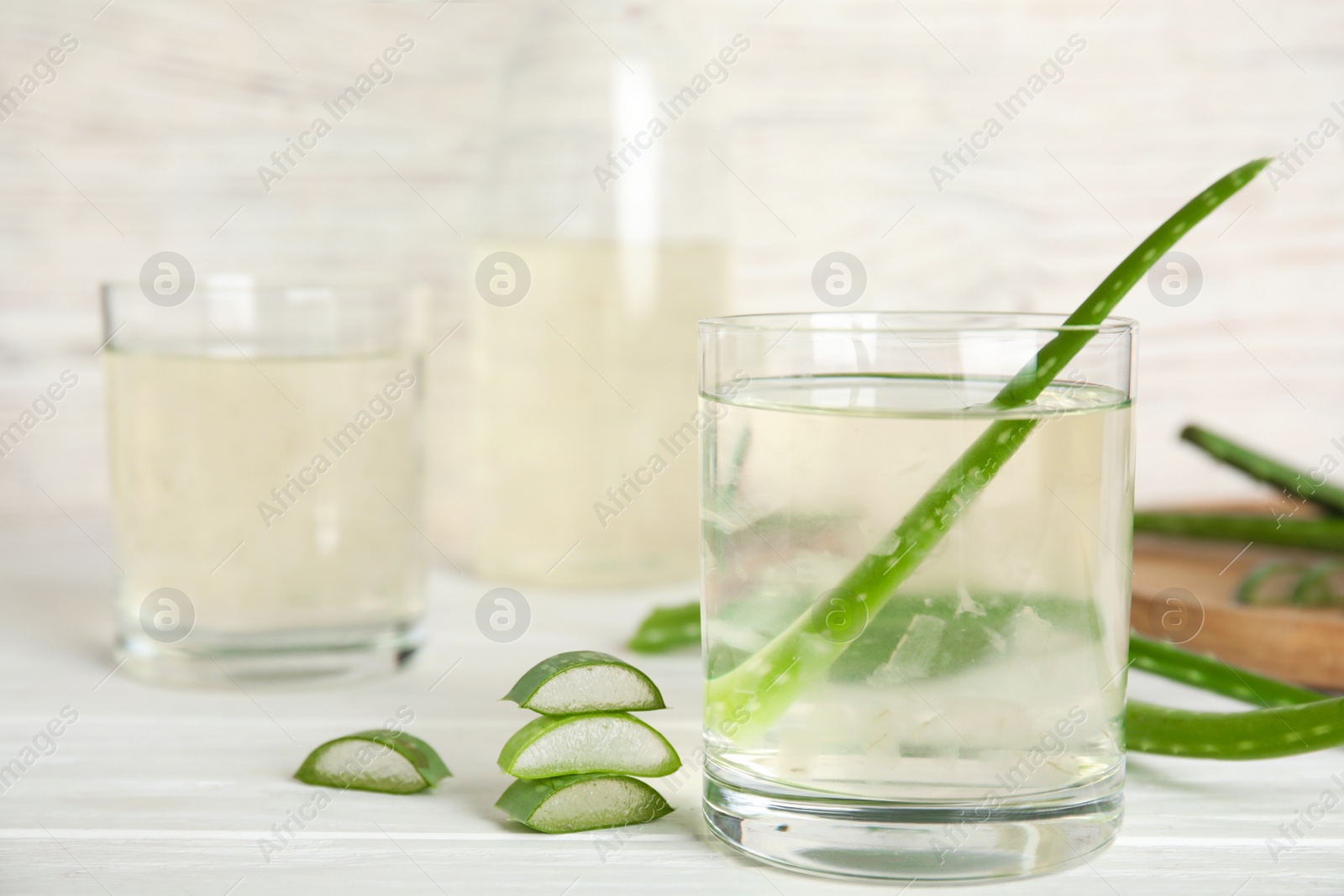 Photo of Fresh aloe drink on light wooden table, closeup. Space for text