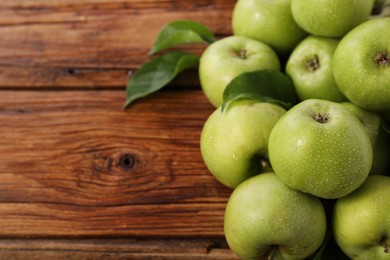 Photo of Fresh ripe green apples with water drops on wooden table. Space for text