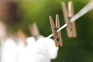 Photo of Washing line with wooden clothespin outdoors, closeup. Drying clothes