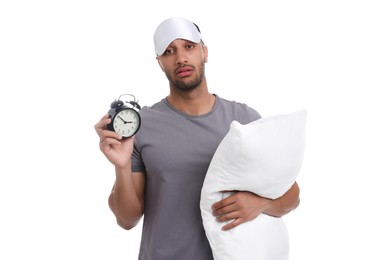 Tired man with pillow, sleep mask and alarm clock on white background. Insomnia problem