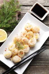 Photo of Raw scallops with spices, dill, lemon zest and soy sauce on wooden table, flat lay