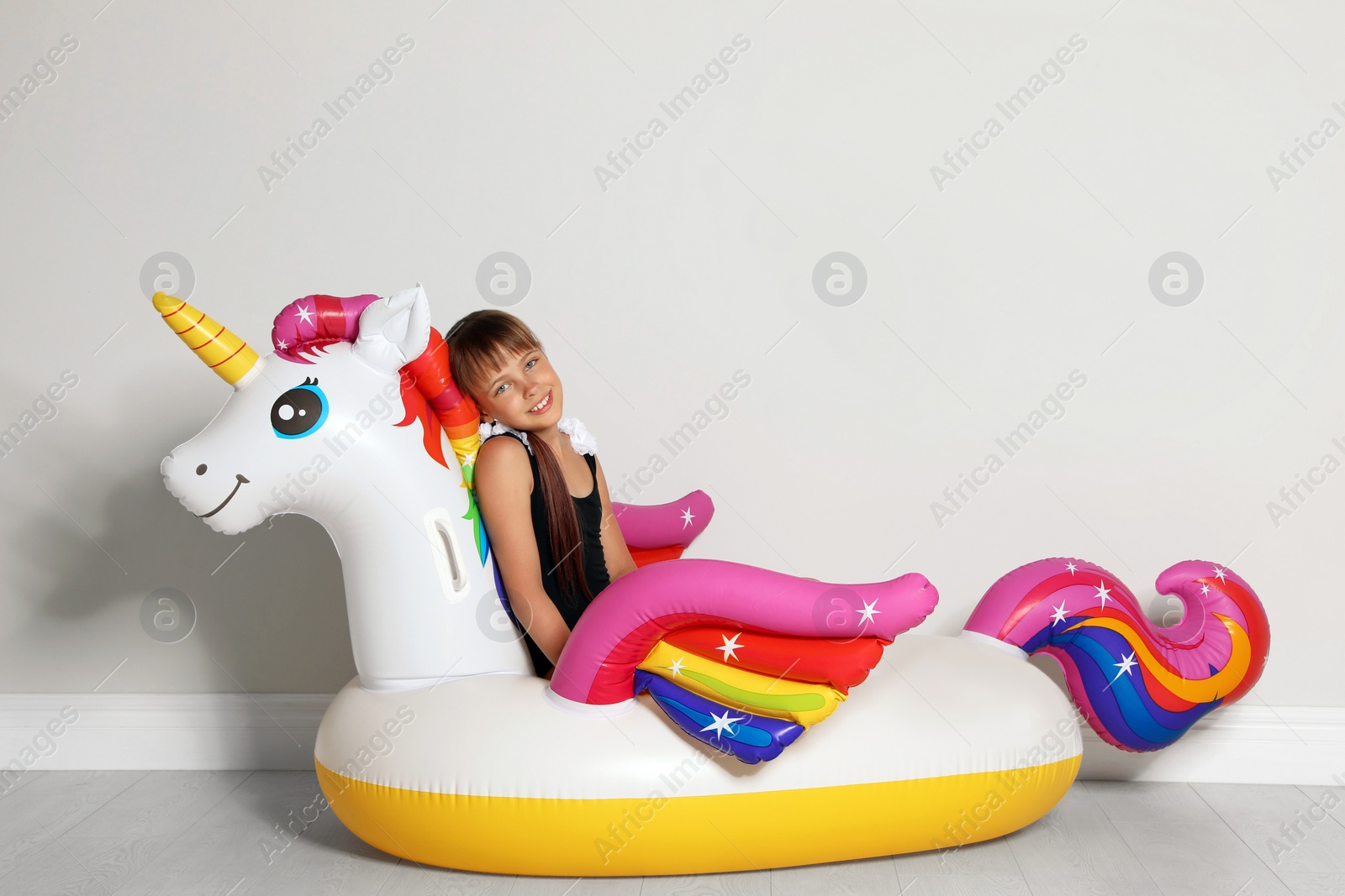 Photo of Cute little girl on bright inflatable ring near light wall