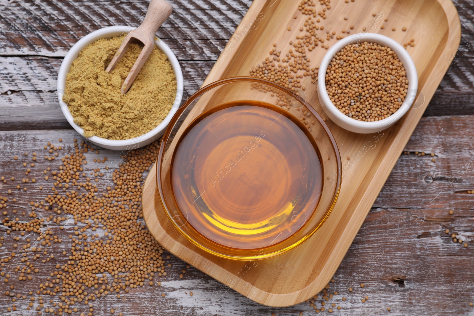 Bowl of natural oil, mustard seeds and powder on wooden table, flat lay Photo of Bowl of natural oil, mustard seeds and powder on wooden table, flat lay