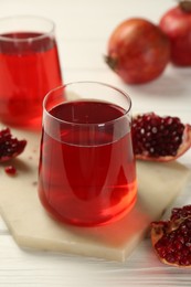 Photo of Tasty pomegranate juice in glasses and fresh fruits on white wooden table, closeup