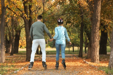Young couple roller skating in autumn park