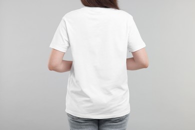 Photo of Woman in white t-shirt on grey background, back view