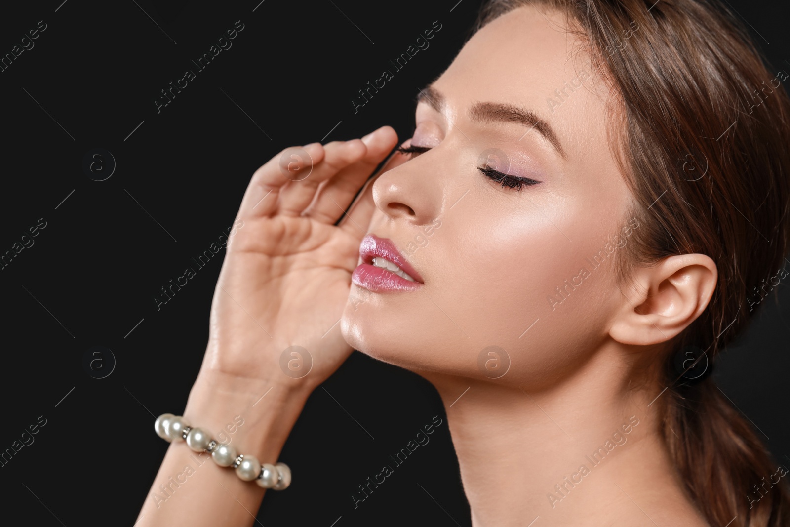 Photo of Young woman wearing elegant pearl bracelet on black background, closeup