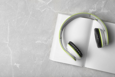 Photo of Modern headphones with hardcover book on grey background, top view. Space for text
