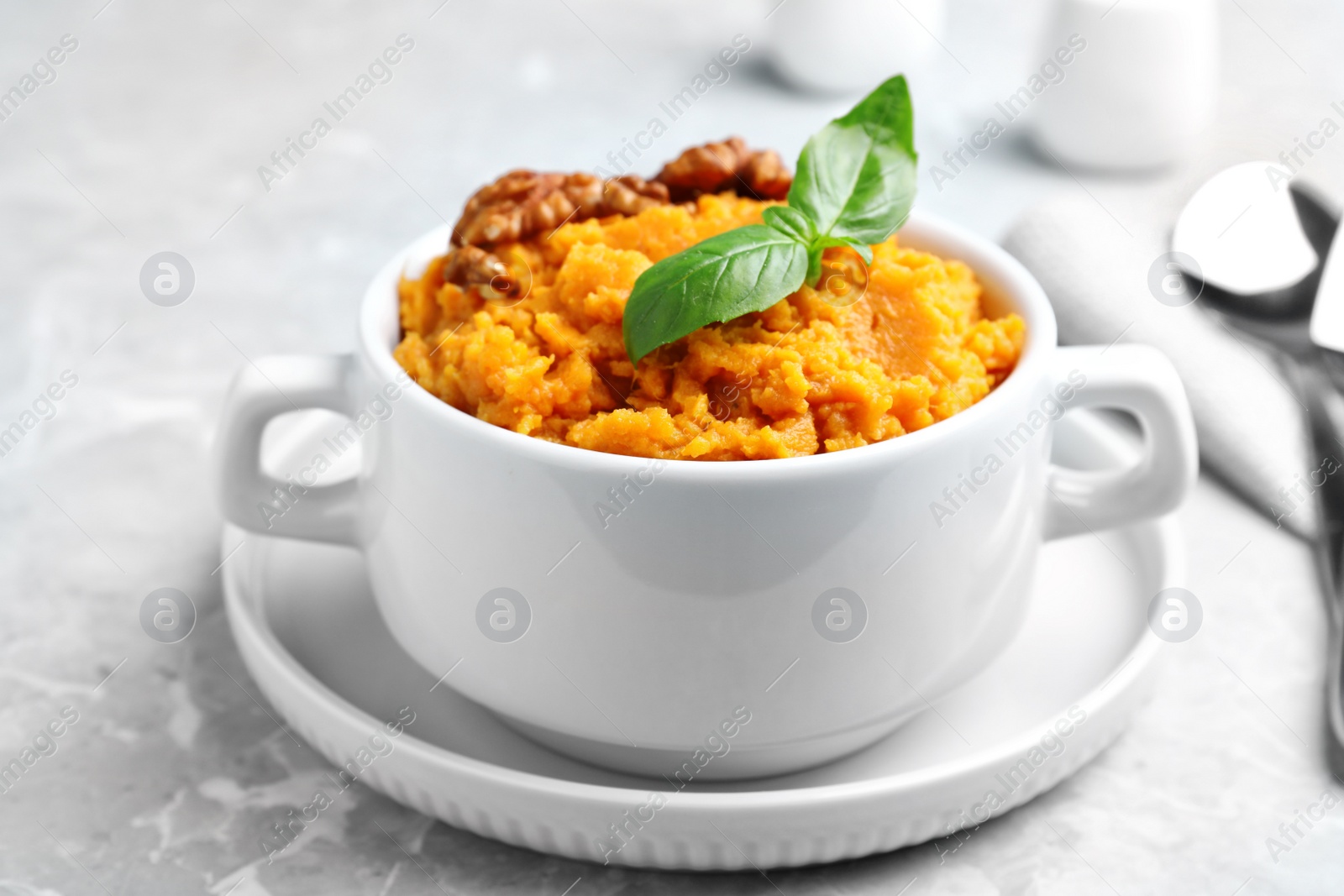 Photo of Bowl of tasty sweet potato puree on grey marble table