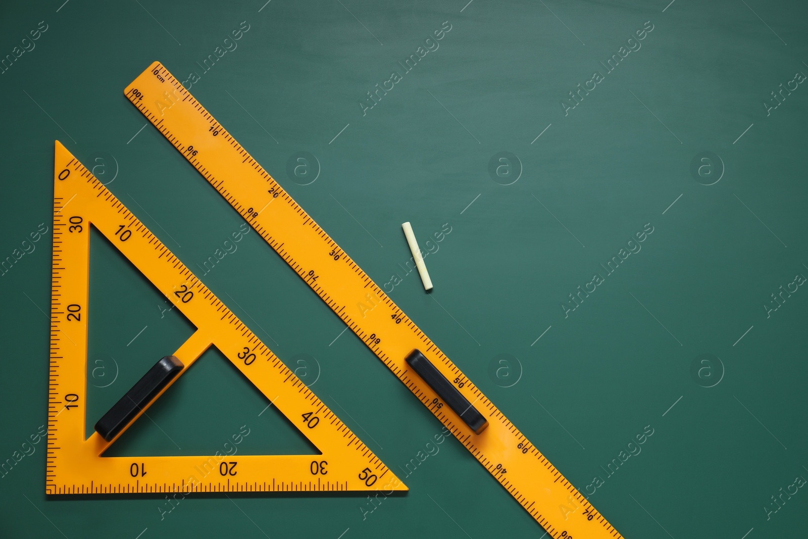 Photo of Triangle, ruler and chalk on green chalkboard, flat lay. Space for text