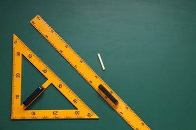 Photo of Triangle, ruler and chalk on green chalkboard, flat lay. Space for text