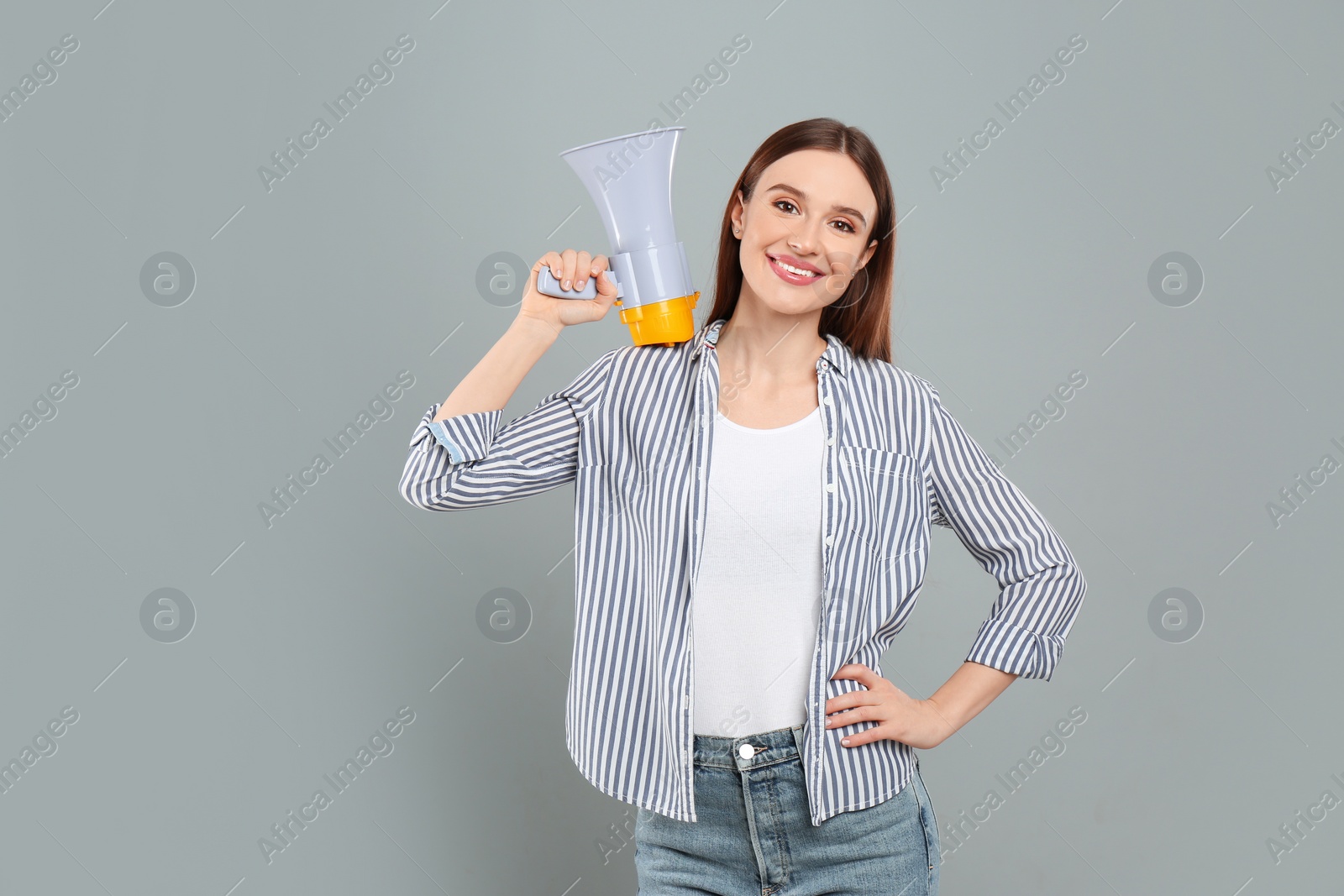 Photo of Young woman with megaphone on light grey background