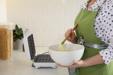 Woman preparing dough near Belgian waffle maker in kitchen, closeup