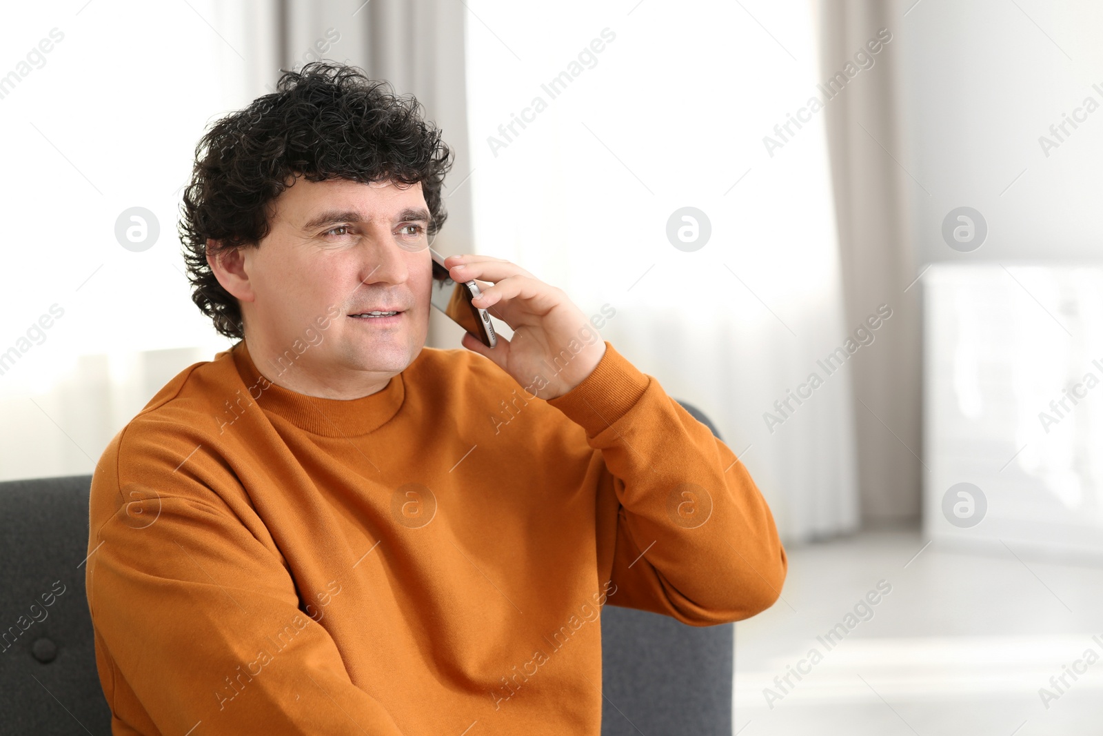 Photo of Mature man talking on mobile phone indoors. Space for text