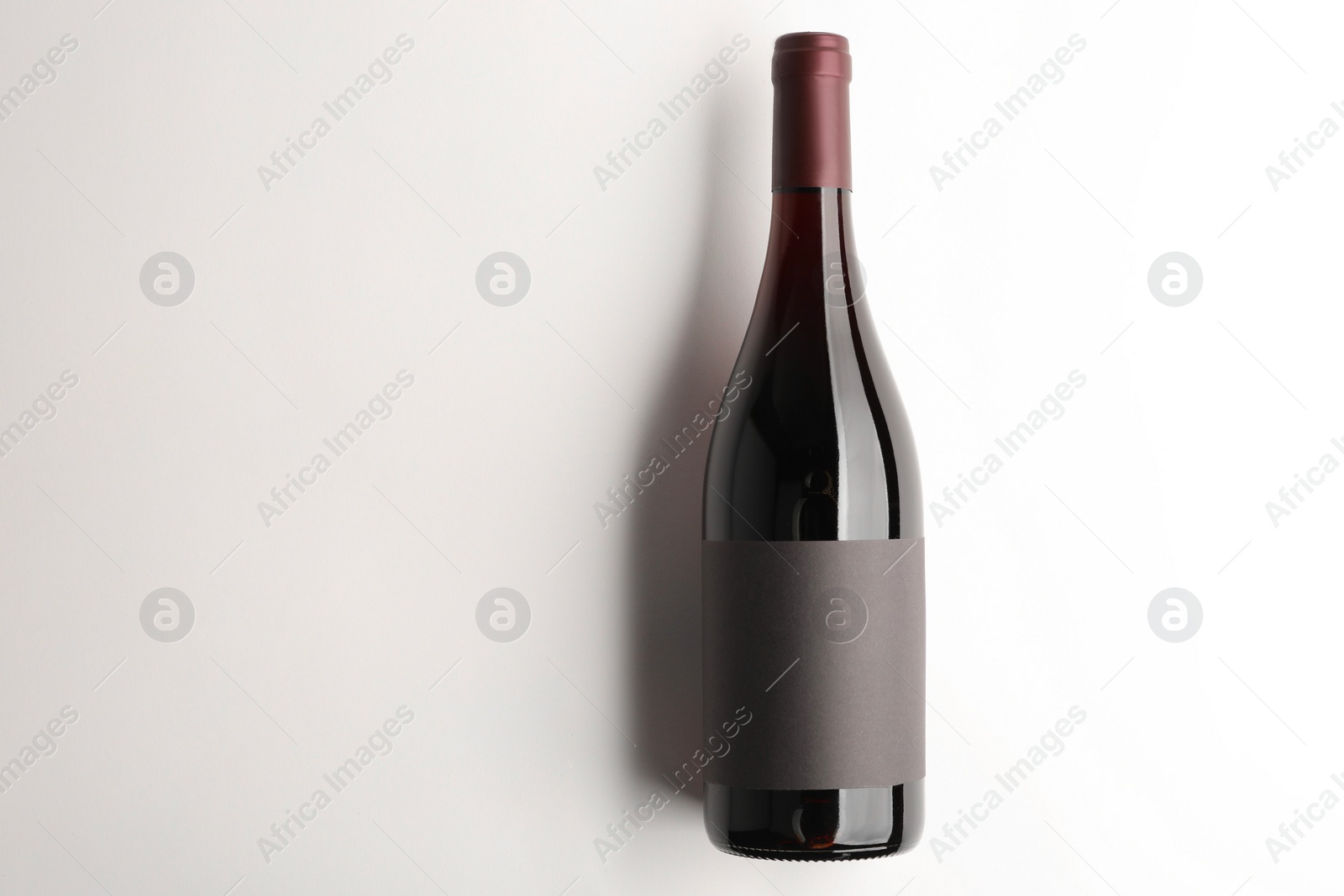 Photo of Bottle of tasty red wine on white background, top view. Space for text