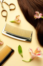 Photo of Hairdresser tools. Brown hair lock, combs, scissors and flowers on pale yellow background, flat lay