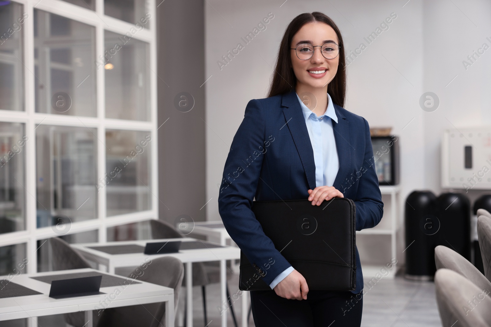 Photo of Happy real estate agent with leather portfolio indoors. Space for text