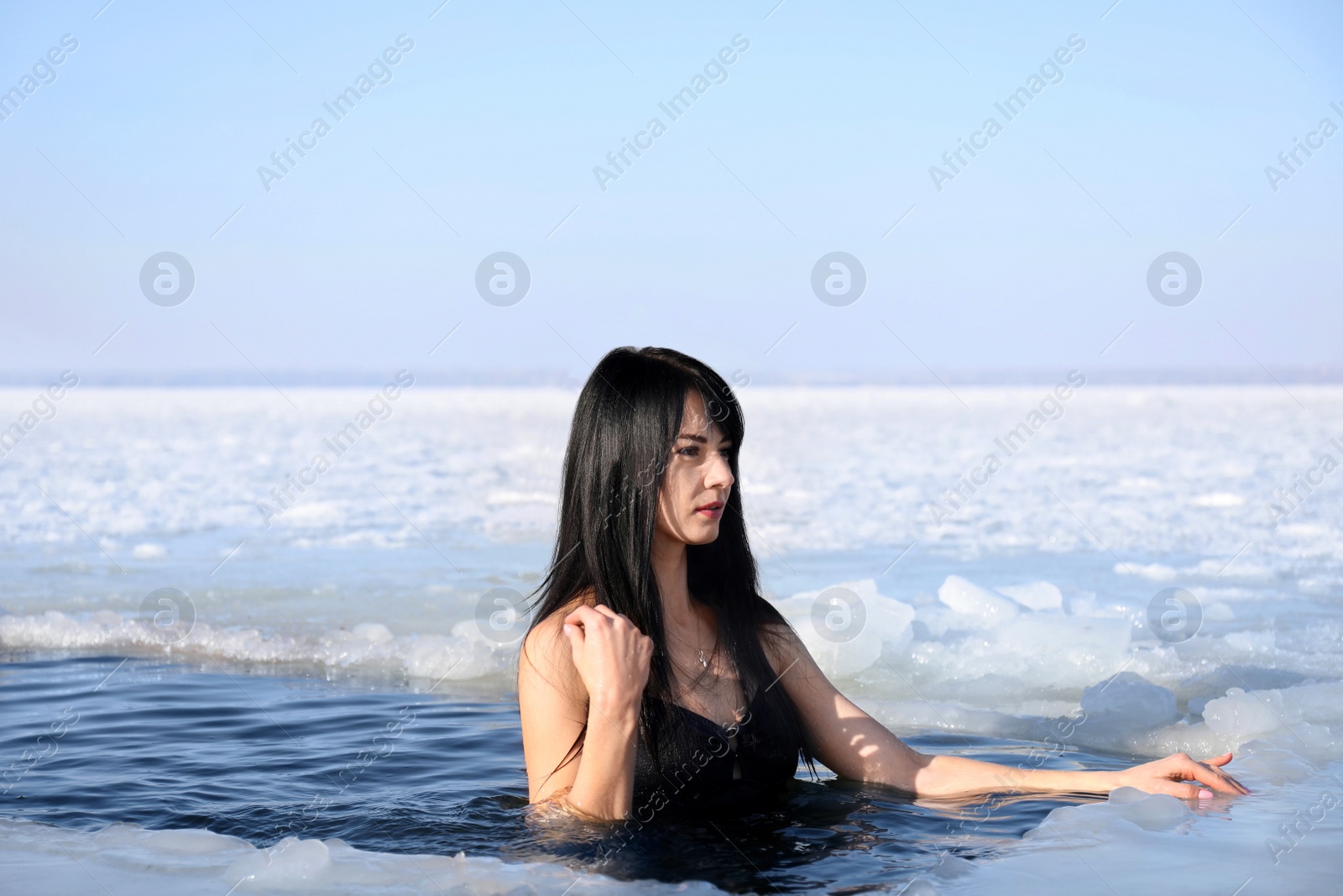 Photo of Woman immersing in icy water on winter day. Baptism ritual