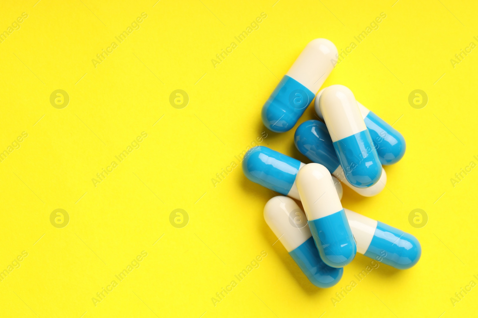 Photo of Many antibiotic pills on light blue background, top view. Space for text