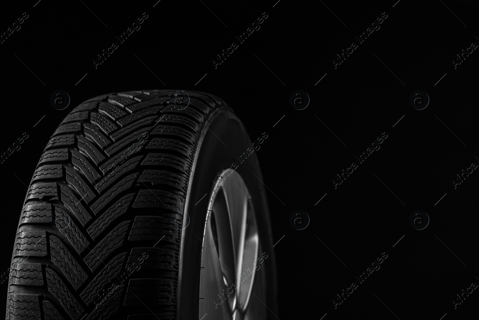 Photo of Wheel with winter tire on black background, closeup. Space for text
