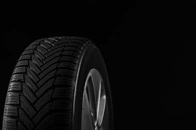 Photo of Wheel with winter tire on black background, closeup. Space for text