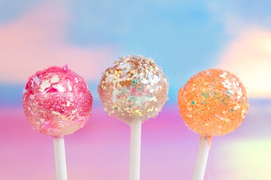 Sweet lollipops with glitter sprinkles on color background