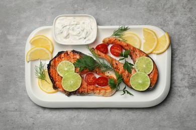 Tasty grilled salmon steaks and ingredients on light grey table, top view