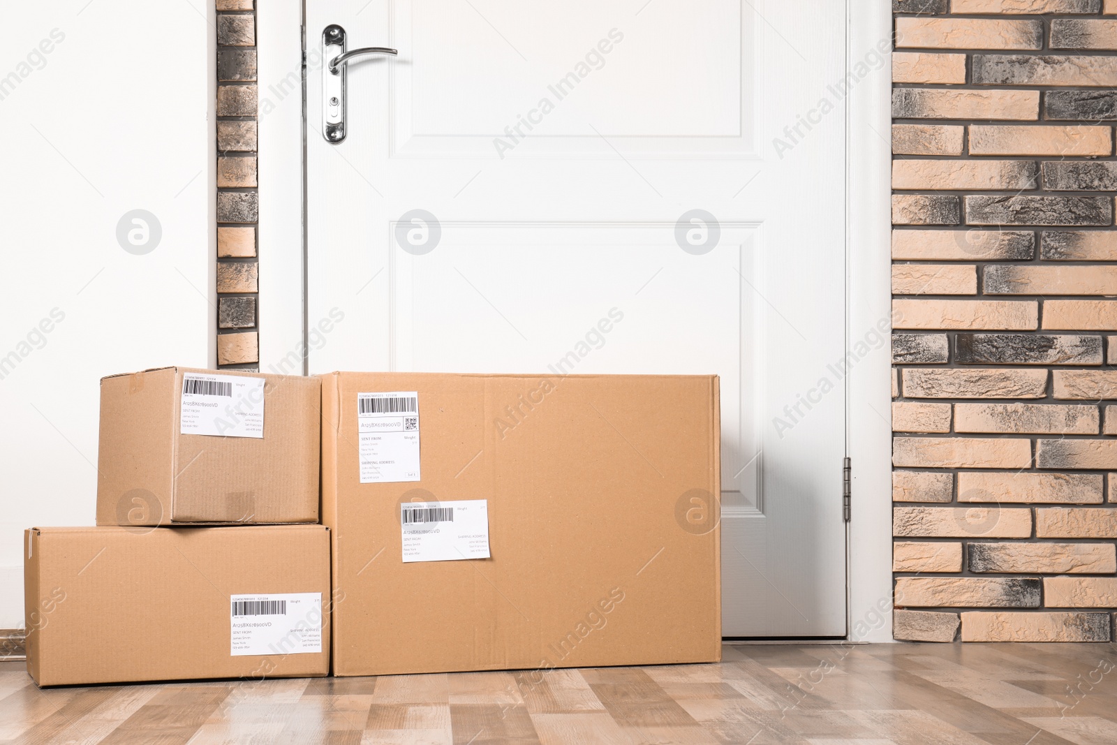 Photo of Cardboard parcel boxes on floor near apartment entrance. Mockup for design