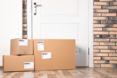 Photo of Cardboard parcel boxes on floor near apartment entrance. Mockup for design