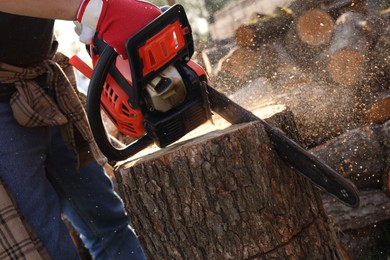 Photo of Man sawing wooden log outdoors, closeup view