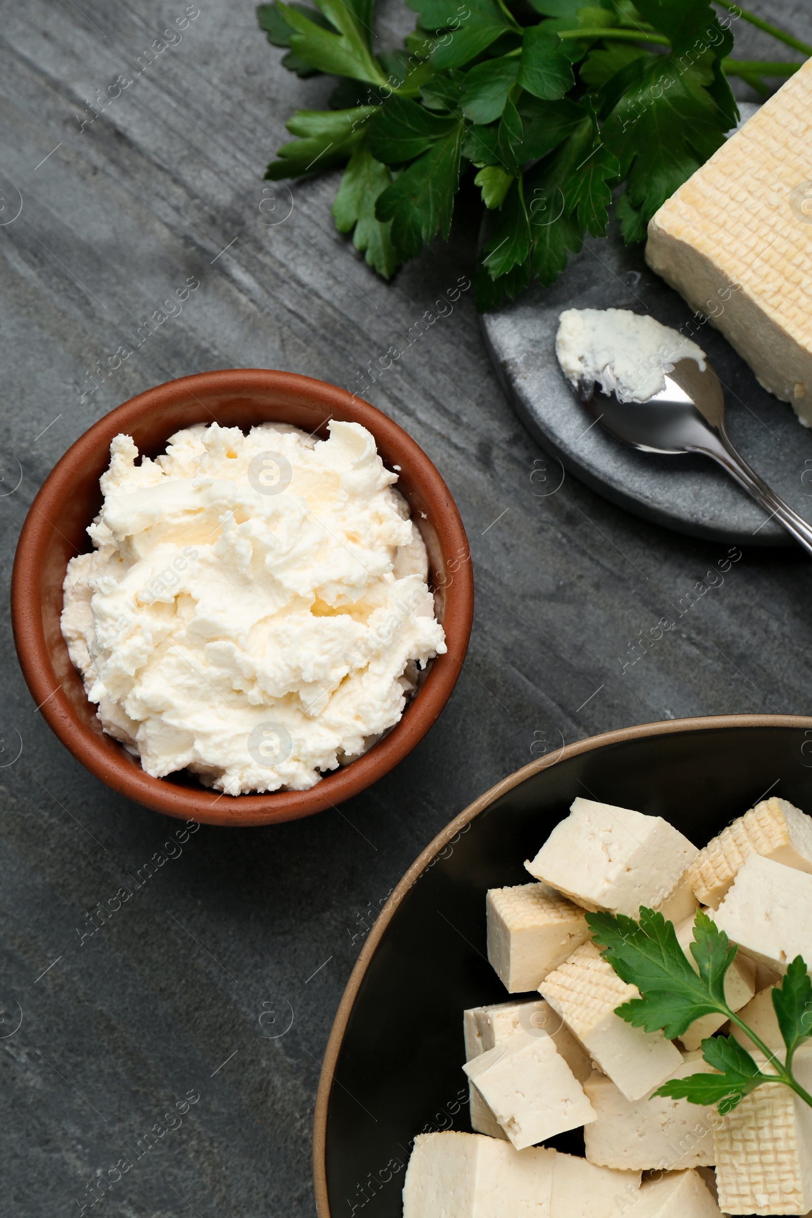 Photo of Delicious tofu cheese and parsley on black table, flat lay