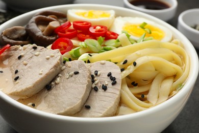 Photo of Delicious ramen with meat and eggs in bowl on table, closeup. Noodle soup