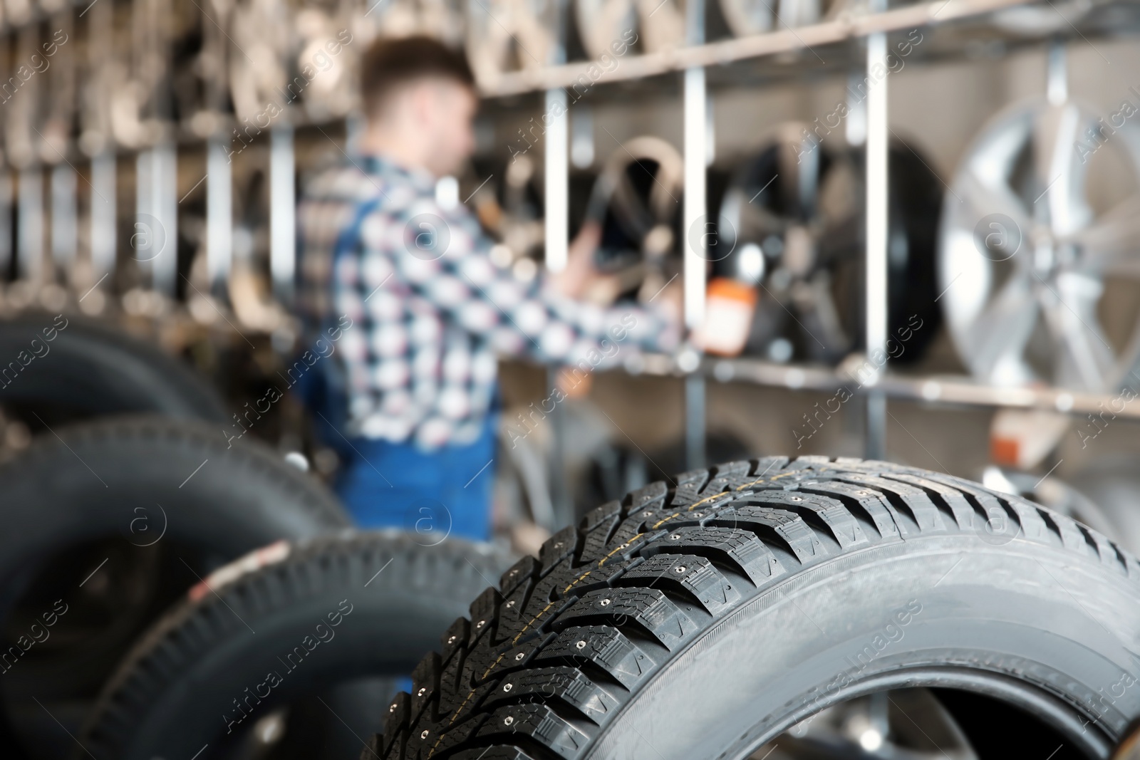 Photo of Car tires and blurred male mechanic on background in automobile service center