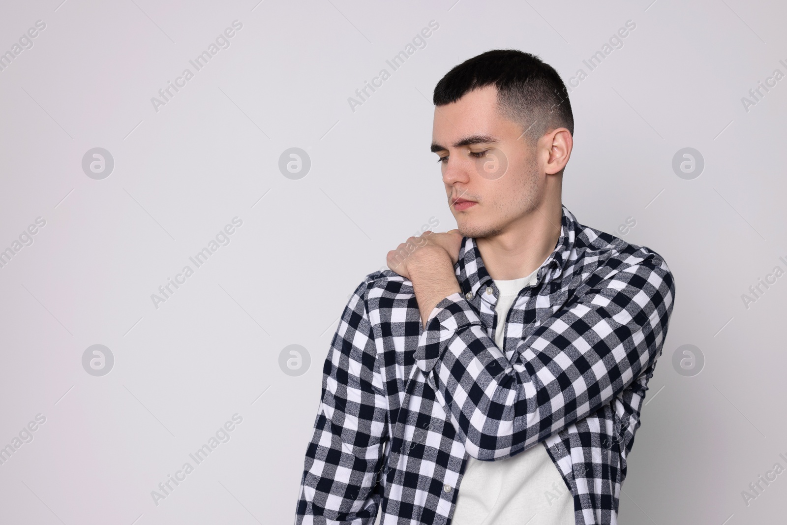 Photo of Man suffering from pain in his shoulder on light background, space for text. Arthritis symptoms