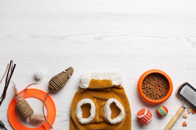 Photo of Flat lay composition with cat clothes, food and accessories on white wooden table. Space for text