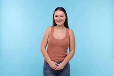 Photo of Smiling woman with dental braces on light blue background