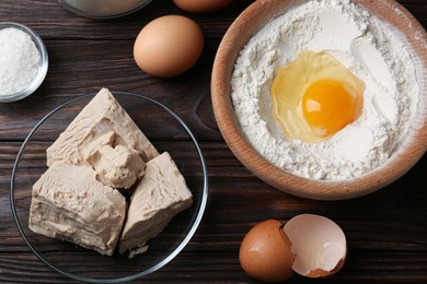 Photo of Compressed yeast, eggs, salt and flour on wooden table, flat lay