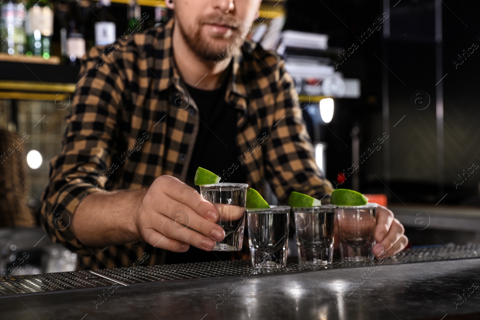 Photo of Bartender with shots of Mexican Tequila at bar counter, closeup