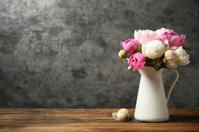 Bouquet of beautiful peonies in vase on wooden table. Space for text