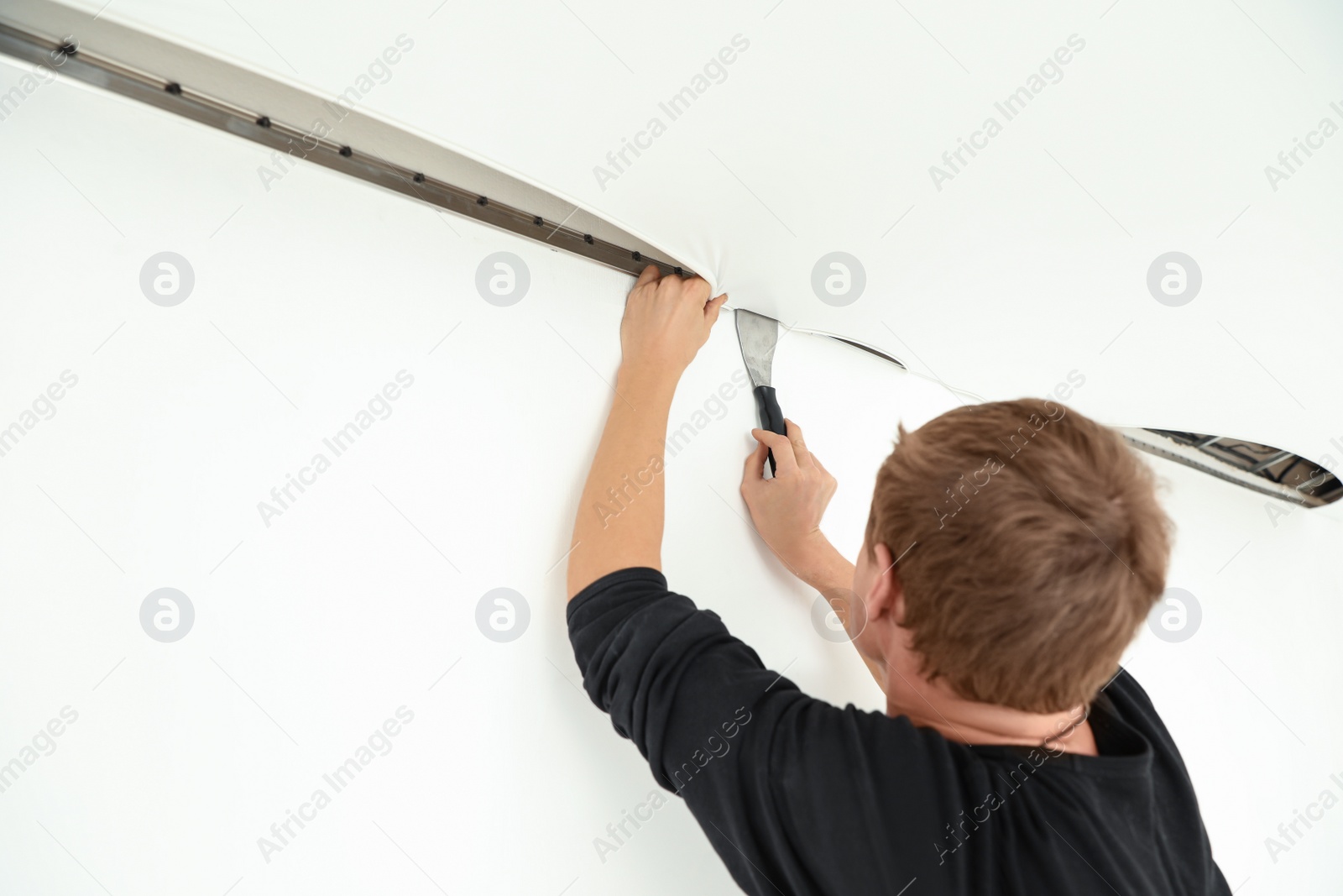 Photo of Repairman installing white stretch ceiling in room