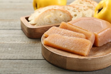 Photo of Tasty sweet quince paste, fresh fruits and bread on wooden table, closeup. Space for text