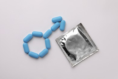 Male sign made of pills and condom on white background, flat lay. Potency problem