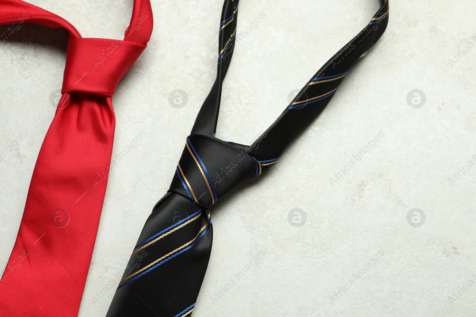 Photo of Two neckties on light textured table, top view. Space for text